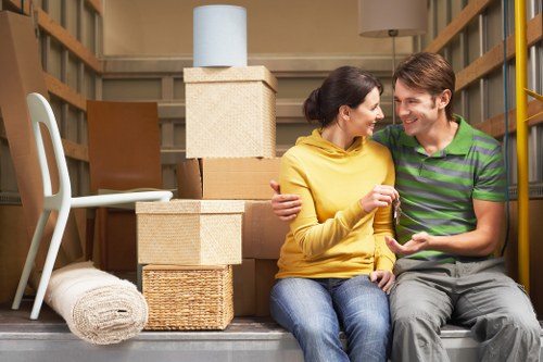 Professional movers carrying furniture through a Kensington property