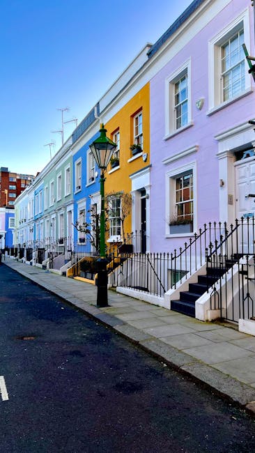 A white exterior wall of a residential property with a decorative white balustrade and a black mailbox fixed to the wall. Above the balustrade is a rectangular street sign indicating 'Portobello Road,